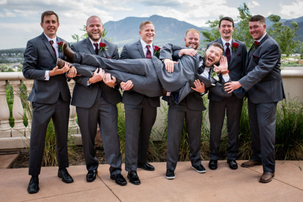 The Pinery At The Hill Wedding In Colorado Springs CO   The Pinery At The Hill Groomsment Goofing Off With Mountain Backdrop 600x400 